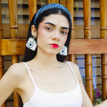Load image into Gallery viewer, A stylish model showcasing a headband and large camera earrings with a serious expression.