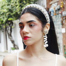 Load image into Gallery viewer, A stylish model posing in a white crop top with a pearl headband and statement earrings.