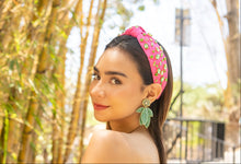 Load image into Gallery viewer, A young woman in a pink headband and green leaf earrings poses outdoors near bamboo.