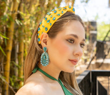 Load image into Gallery viewer, A summer fashion look featuring a yellow jeweled headband and green attire against a bamboo backdrop.