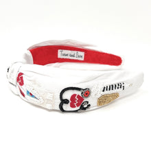 Load image into Gallery viewer, Close-up of a woman wearing a fun nurse-inspired statement headband with heart and medical symbol accents.