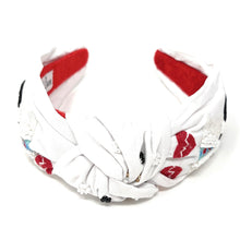 Load image into Gallery viewer, Fashion model wearing a novelty nurse-inspired headband paired with bold red statement earrings in sunlight.