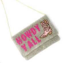 Load image into Gallery viewer, Model in a black dress carrying a handmade beaded envelope clutch that reads “Howdy Y’all” in vibrant pink beads.